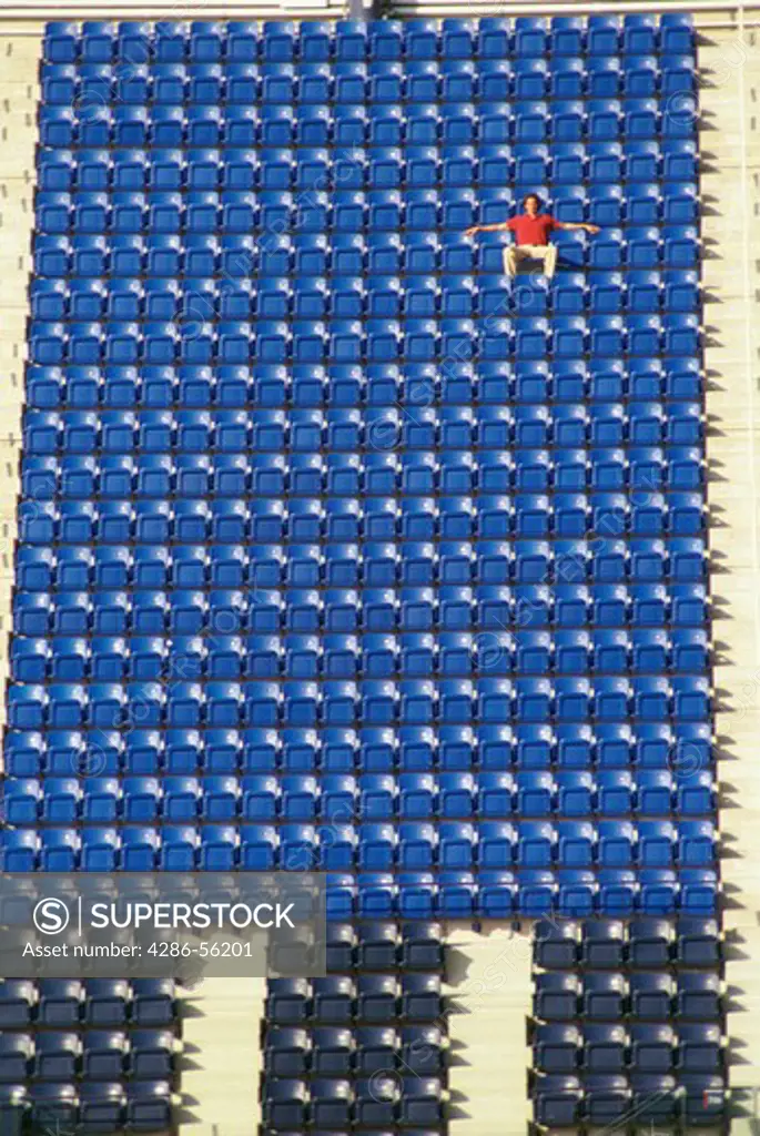 Man standing alone in stadium bleachers. 
