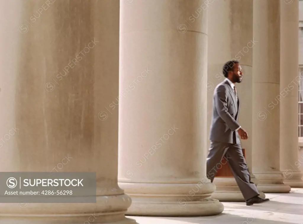 African American businessman leaning against columns