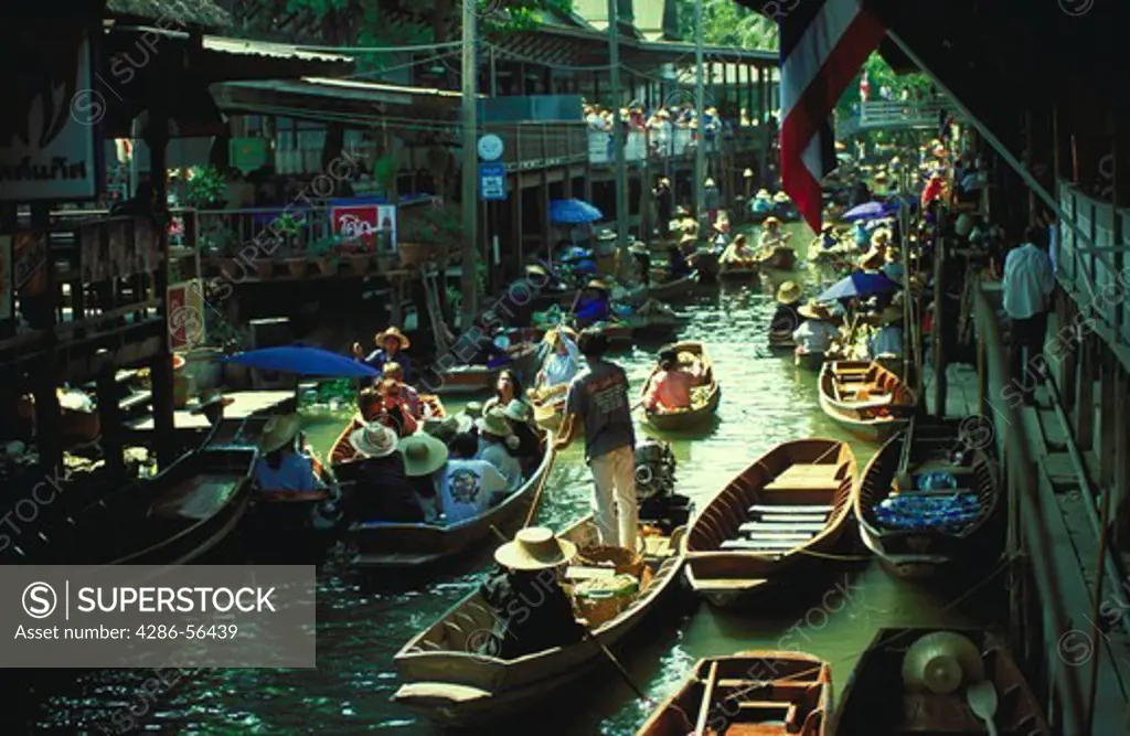 View of tourists and venders crowded on boats at a floating market in Thailand.