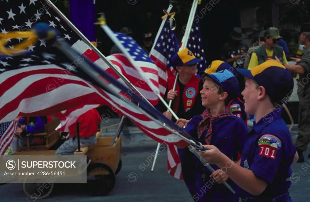 Cub Scouts carrying flags in a parade.