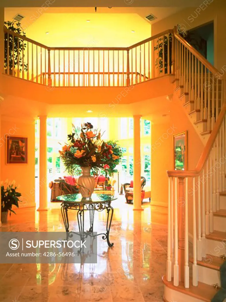 Large vase of flowers adorns table in elegant foyer with staircase. Property Release available.