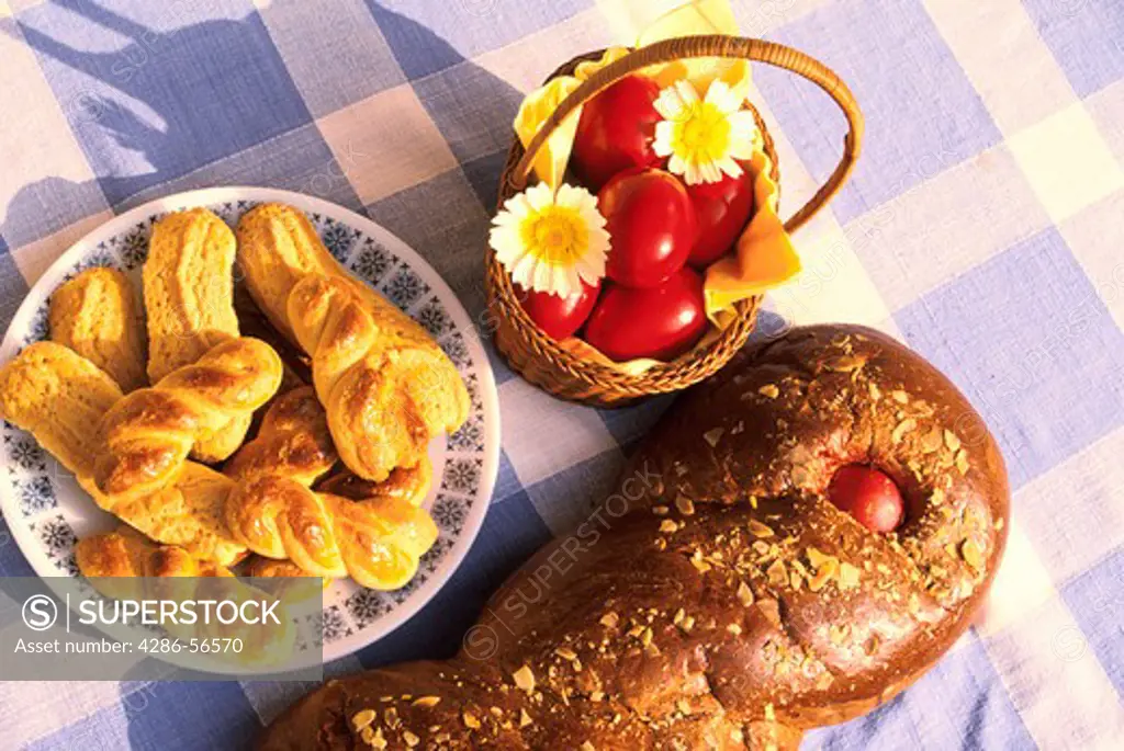 Traditional Greek food: Easter bread (Tsoureki) and bisquits (Koulourakia) on blue & white checkerboard tablecloth.
