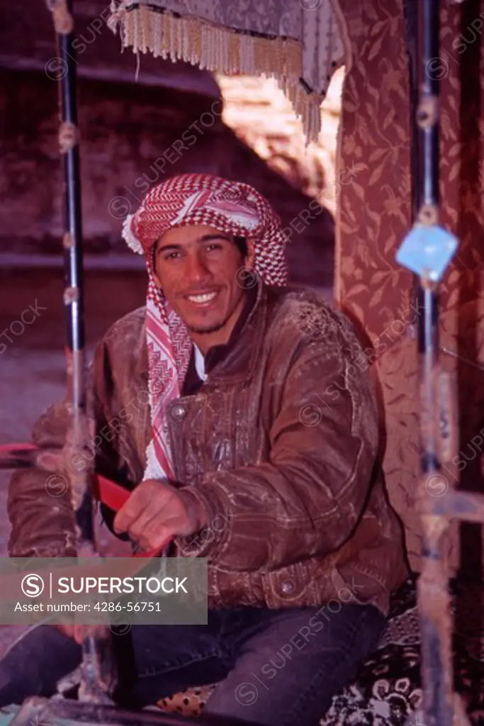 Portrait of a young, smiling Jordanian man who takes Tourists through the Siq on his two - wheeled buggy. Petra, Jordan.  