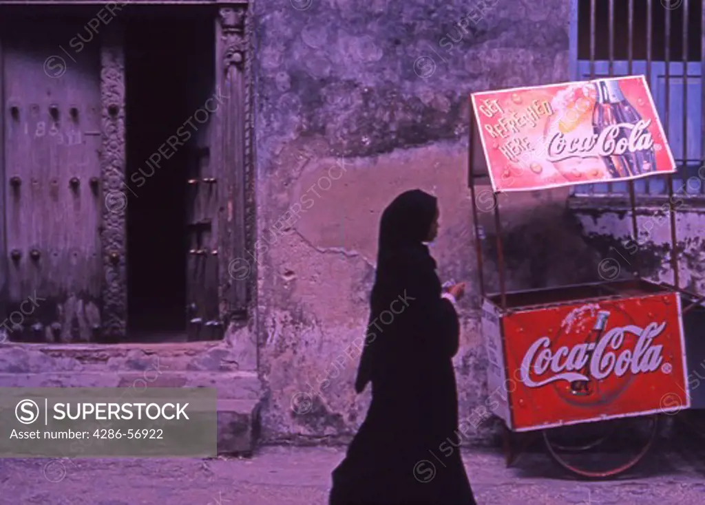Old wooden door, Zanzibari woman and mobile Coca Cola stall.  Stone Town. Zanzibar. Tanzania.