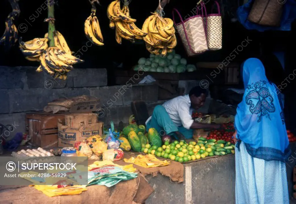 Zanzibari woman in traditional khanga shopping at a fruit and vegetable stall in the Central Market. Stone Town. Zanzibar. Tanzania. East Africa.