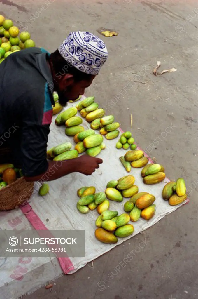 A Zanzibari man arranging fresh vegetables for sale outside Stone Town Central Market. Zanzibar. Tanzania. East Africa.