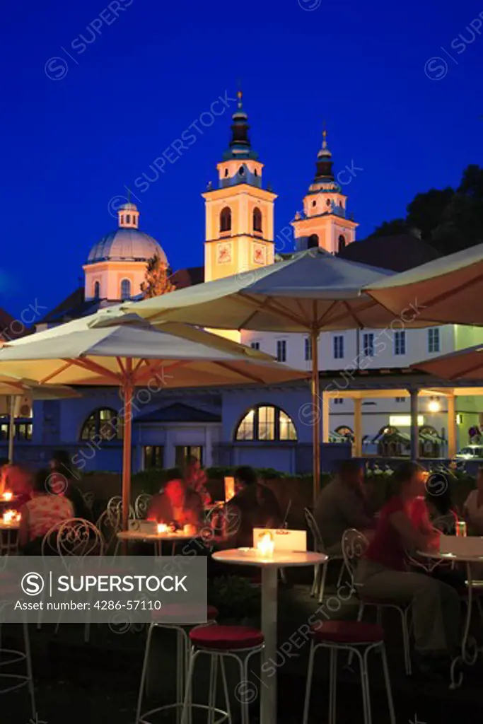 Slovenia. Ljubljana. Cafe Bar and Illuminated Cathedral of St Nicholas at night.