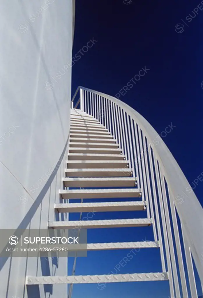 Silver metal steps ascending around the side of a cylinder shaped structure. 