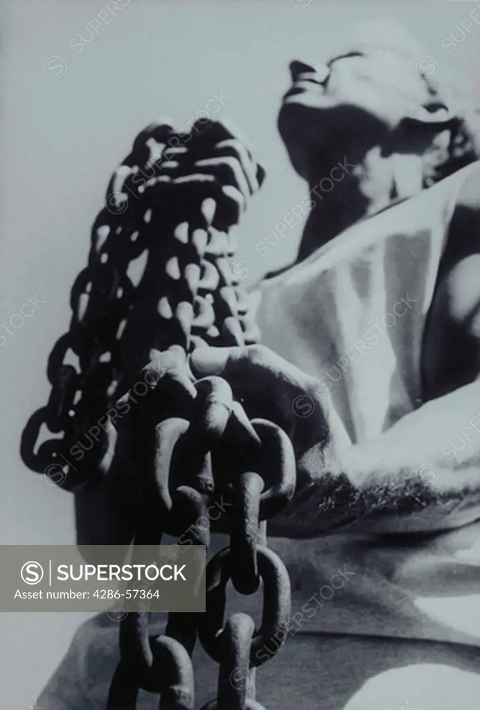 View looking up at a thirty year old man holding a large, heavy chain in his hands.
