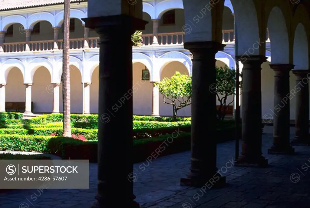 Looking in to the sunshine from the shadows beneath the columns surrounding the colonial courtyard of Franciscan Museum at Iglesia (church) Santo Domingo, Old Town, Quito, Ecuador.