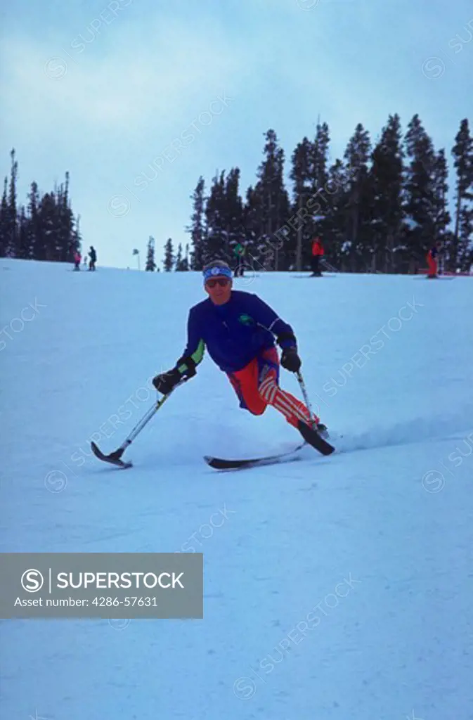 A sixty-six (66) year old disabled man skiing down a mountain using a special ski and special poles.