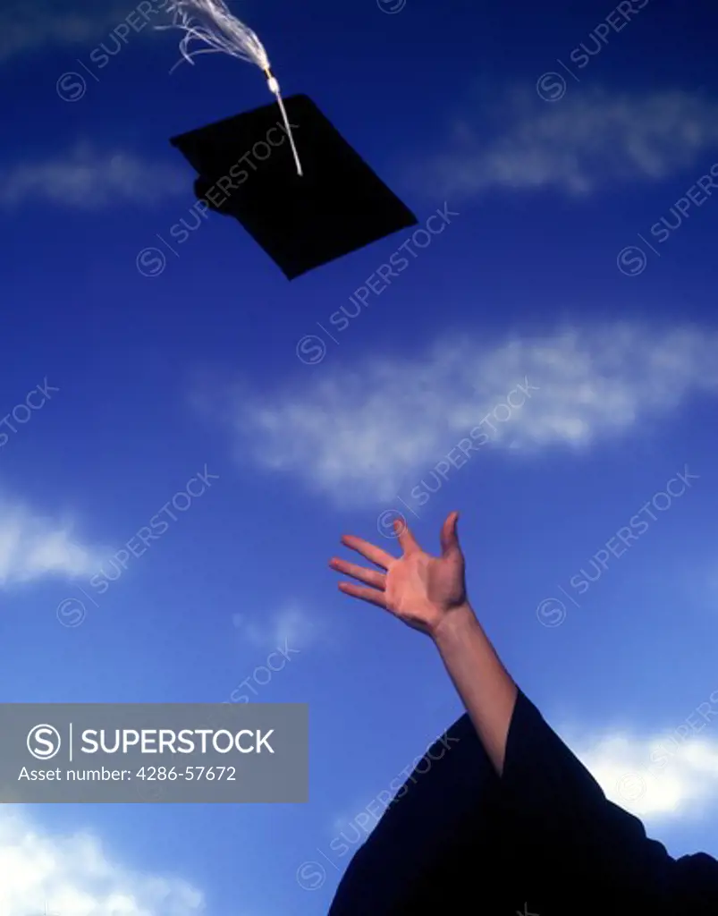 A graduation cap flies up against a blue sky after being tossed by a graduate.
