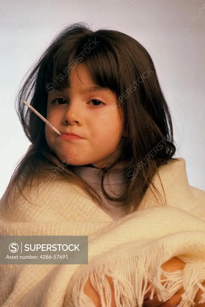 Close-up of a young girl with a thermometer in her mouth and wrapped in a blanket.