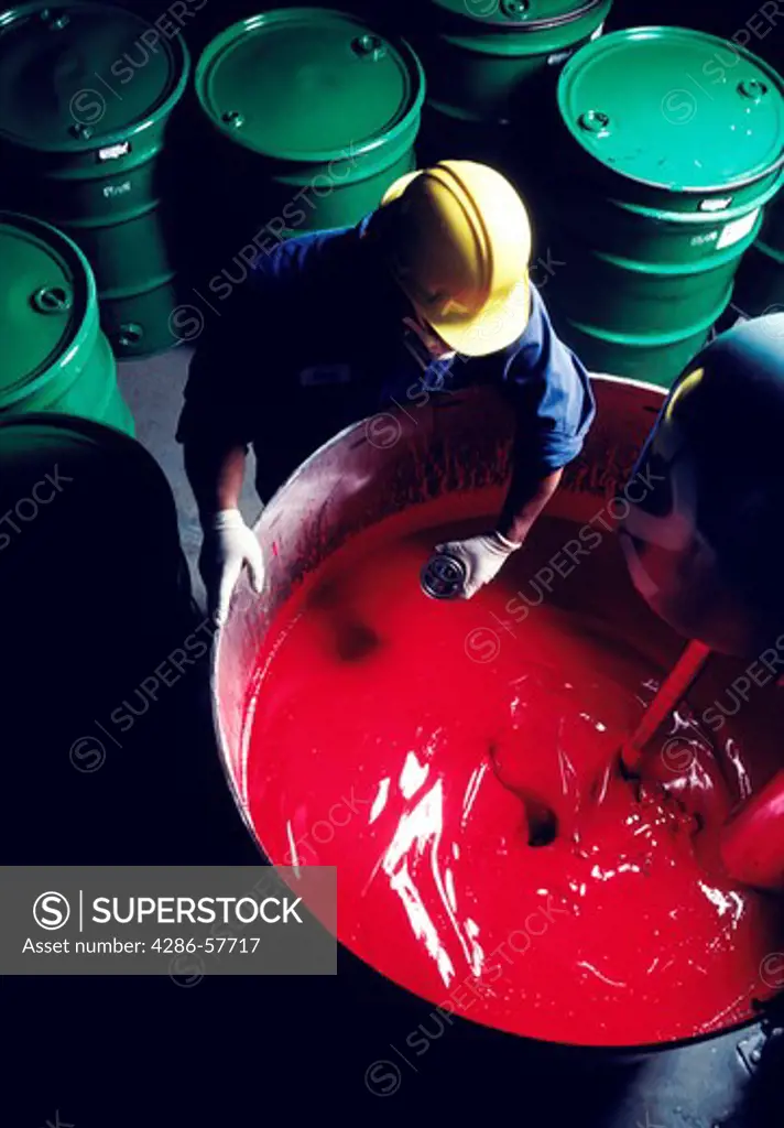 Aerial view of a man wearing gloves and a hard hat working with sulfur that is contained in 50 gallon drums.