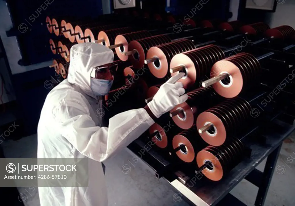 An engineer in protective covering at a manufacturing plant for computer data disks.