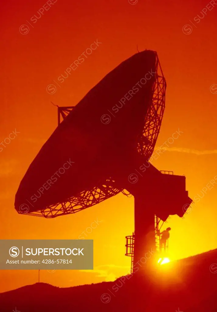 Close-up of a large communication microwave dish as the sunsets behind it.