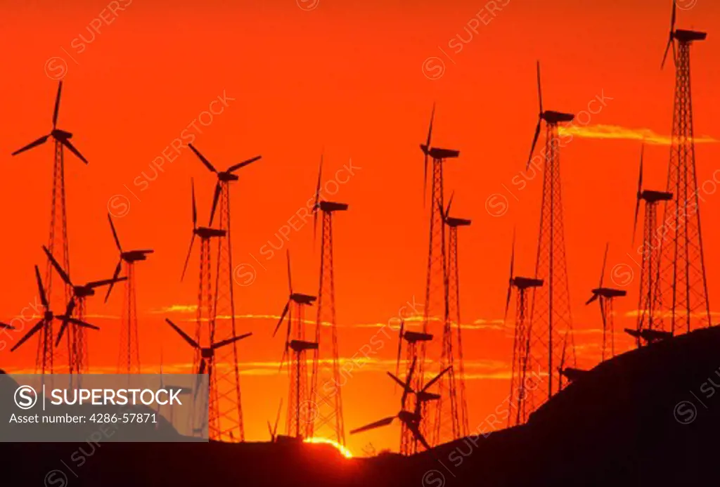 Silhouette of wind turbines generating electricity at a windmill farm in California at sunset.