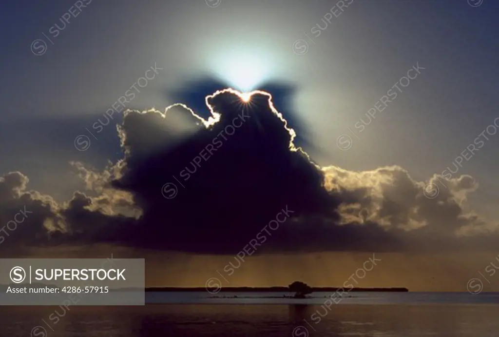 Sun rays radiate from behind clouds at sunrise over Florida Bay, Everglades National Park, Florida.