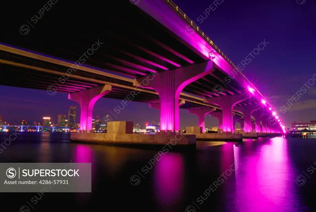 Rickenbaker Causeway bridge over Biscayne Bay in Miami, Florida as magenta lights illuminate the bridge as part of a beautification project.