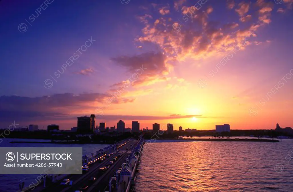 Sunset illuminates the sky above the downtown skyline of Saint Petersburg, Florida. View is overlooking The Pier, municipal pier and entertainment complex, the beach on the right  and buildings of downtown.