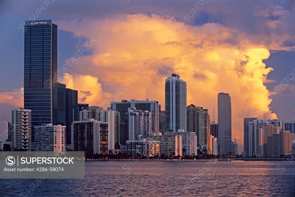 Rising sun lights cloud backdrop to highrise office and residential buildings along Brickell Avenue and Biscayne Bay, Miami, Florida.