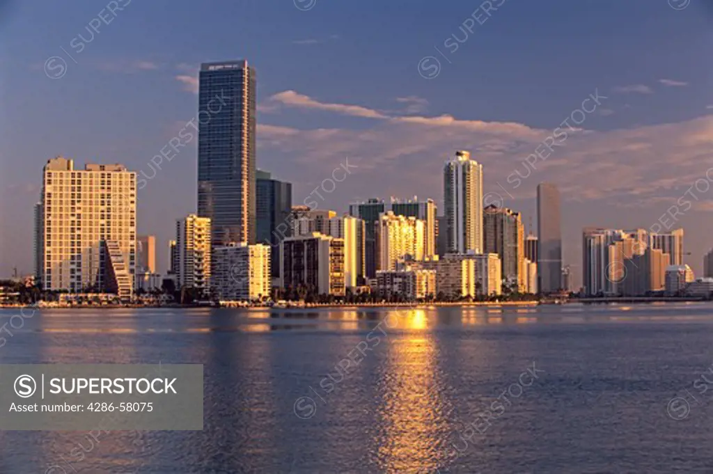 Golden rising sun reflects from highrise office and residential buildings along Brickell Avenue and reflects on Biscayne Bay, Miami, Florida.  