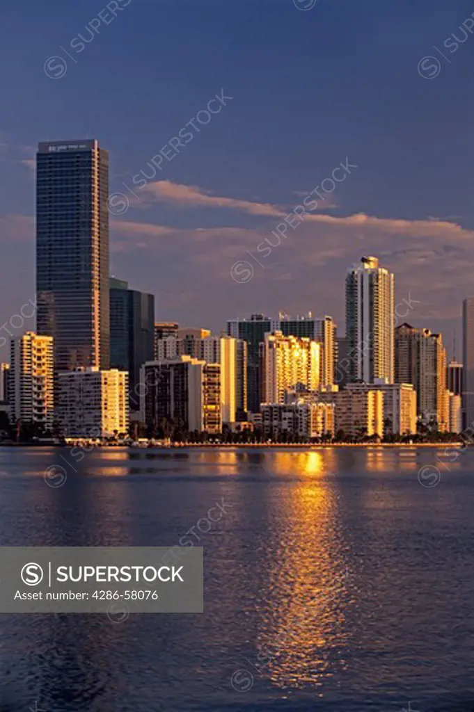 Golden rising sun reflects from highrise office and residential buildings along Brickell Avenue and reflects on Biscayne Bay, Miami, Florida.