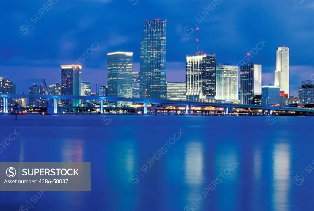Miami, FL, skyline reflecting in Biscayne Bay enveloped in deep blue shroud of evening.