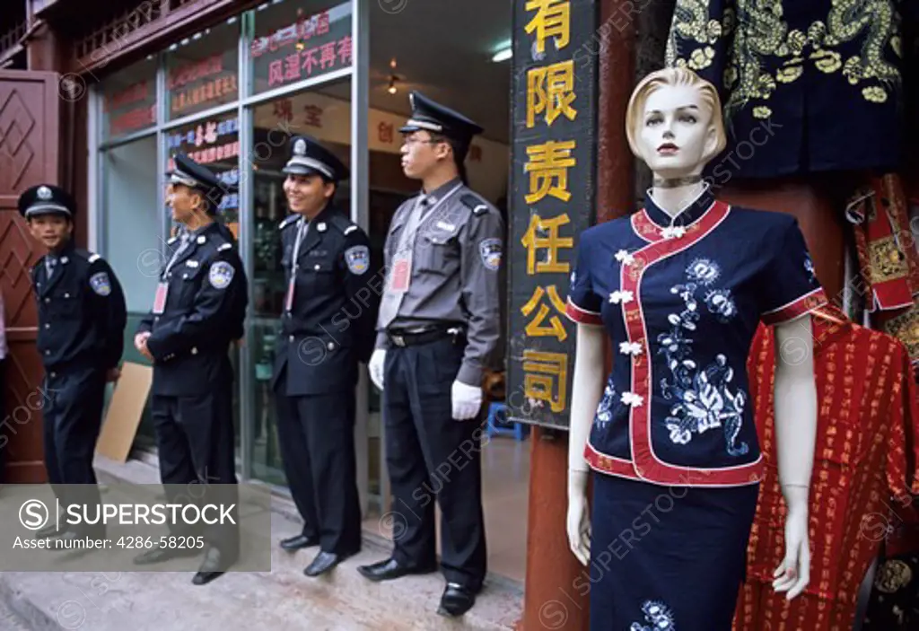 Police officers watch street celebration in shopping district, Duyun, Guizhou Province, China
