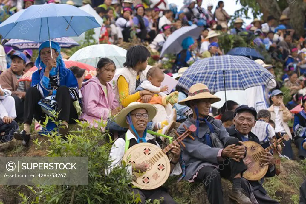 Sani ethnic minority musicians and families gather at outdoor amphitheater during the annual June Torch Festival, Long Lake Town, Shilin County, Yunnan Province, China.