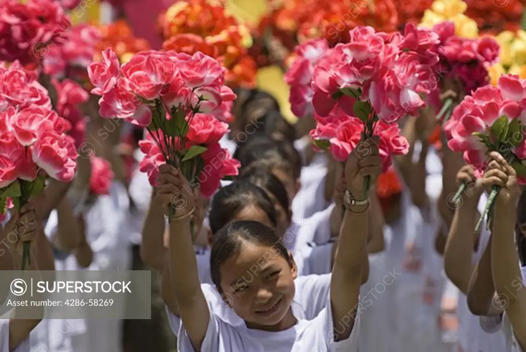 Raising flower bouquets Sani ethnic minority girls march as part of annual June Torch Festival in Long Lake Town, Shilin County, Yunnan Province, China.