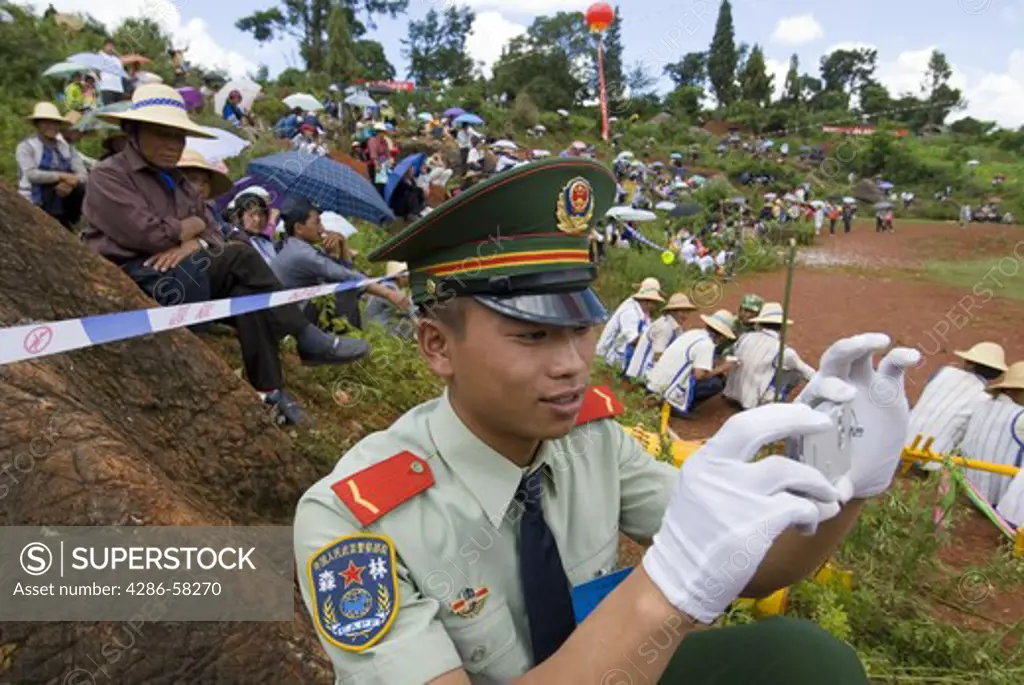 Local police officer takes photographs at annual June Torch Festival, Long Lake Town, Shilin County, Yunnan Province, China.