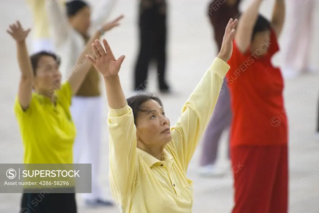 Middle aged women perform predawn taichi exercies in city park, Geju, Honghe County, Yunnan Province, China.