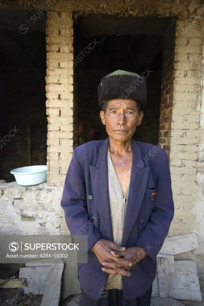 Elderly member of Yani ethnic minority group proudly poses with Communist Party member red lapel pin outside his modest home, Qingkou Village, Yuanyan County, Yunnan Province, China.