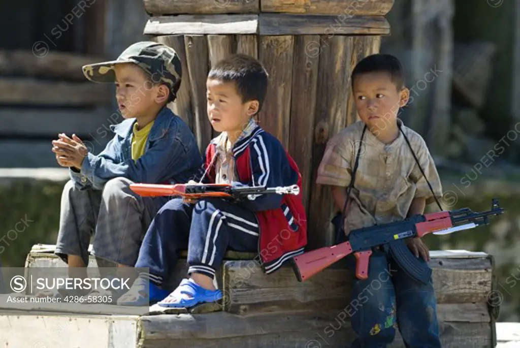 Mischievous boys play with toy plastic rifles in village square of Qingkou Village, Yuanyan County, Yunnan Province, China. 