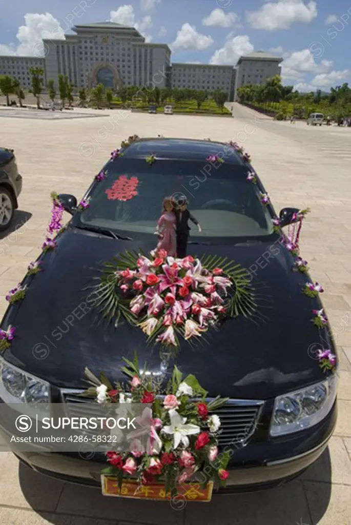 After transporting bride and groom to Honghe County administration complex for wedding photos, imported luxury automobile decorated with fresh flowers awaits their return, Mengzi, Yunnan Province, China.