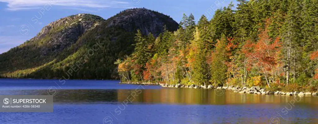 Fall colors dot shore of Jordan Pond, with The Bubbles in distance, Acadia National Park, Maine.