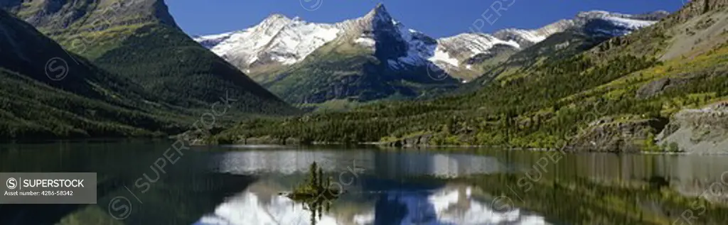 Mirror smooth Lake Saint Mary surrounds Wild Goose Island in Autum, Glacier National Park, Montana.