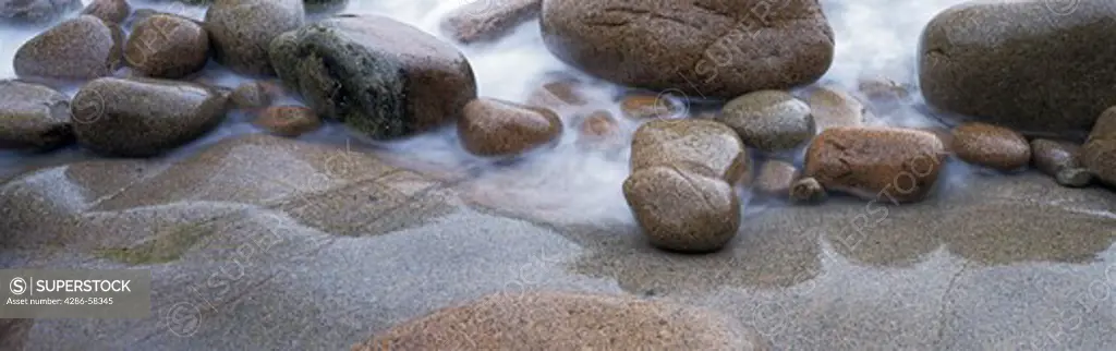 Waves wash against time worn boulders along Atlantic coast, Acadia National Park, Maine.