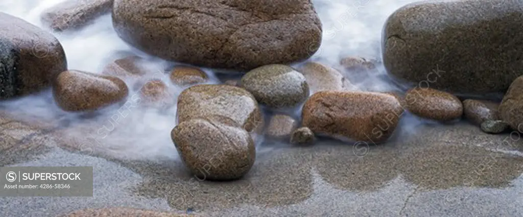 Waves wash against time worn boulders along Atlantic coast, Acadia National Park, Maine.