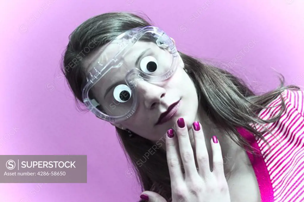 Young woman wearing goggles onto which is attached two doll's eyes.  