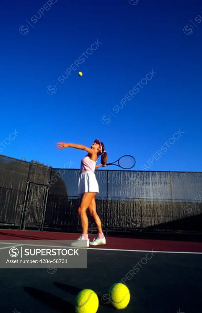 Attractive healthy woman serving on colorful tennis court