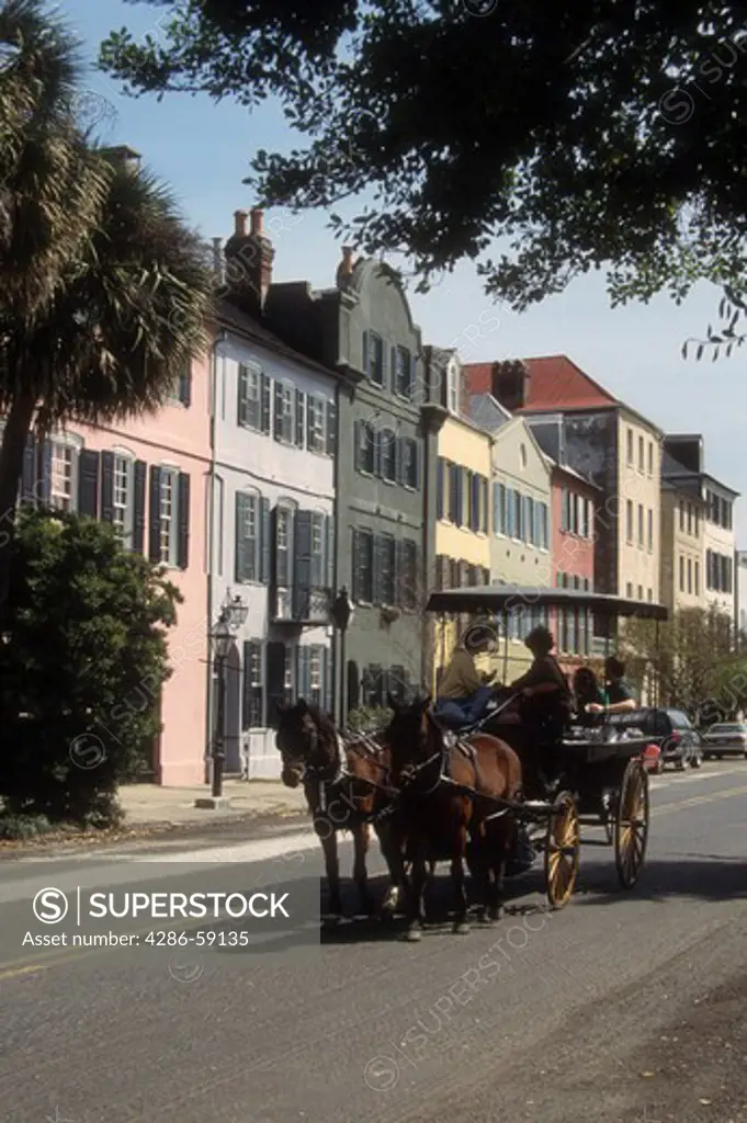Tourists in horse drawn carrriage view the famous and historic Rainbow Row in Charleston, SC.