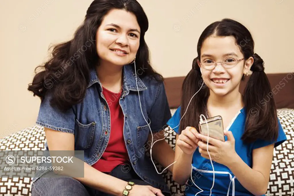 Portrait of a mature woman with her daughter listening to an mp3 player