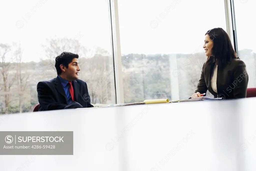 Businessman and a businesswoman sitting at a conference table in an office