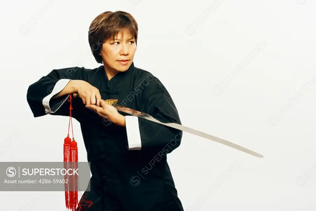 Close-up of a mature woman practicing martial arts with a sword