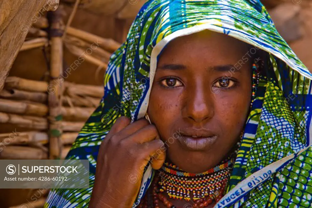 This Fulani woman has walked to Torodi, Niger from a village ten miles away to attend the weekly market. She wears her brightest newest clothing to show off on market day, together with her bead chokers and beaded earrings. Her jewelry is handmade and can take days to make. NOT MODEL RELEASED. EDITORIAL USE ONLY.
