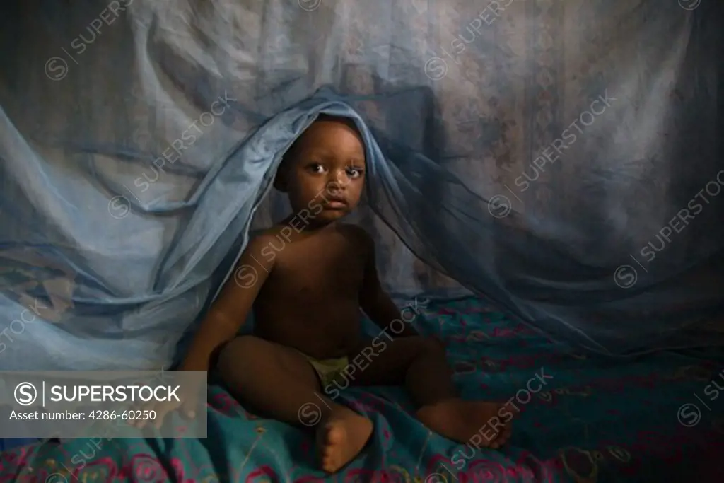 Child climbing out from under mosquito net in Kano, Nigeria.  Sleeping under a long lasting insecticide treated net every night prevents malaria.  Malaria, which is transmitted through the bite of an infected mosquito, is a major killer of children under five and pregnant women in Nigeria and the developing world. NOT MODEL RELEASED. EDITORIAL USE ONLY.