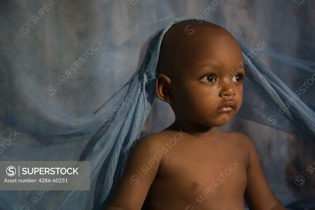 Child climbing out from under mosquito net in Kano, Nigeria.  Sleeping under a long lasting insecticide treated net every night prevents malaria.  Malaria, which is transmitted through the bite of an infected mosquito, is a major killer of children under five and pregnant women in Nigeria and the developing world. NOT MODEL RELEASED. EDITORIAL USE ONLY.