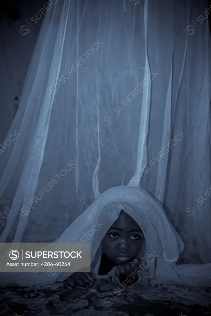A child in the Garki area of Abuja peeks out from under a Permanet long lasting insecticide treated mosquito net.  Sleeping under a mosquito net every night prevents malaria, which is transmitted through the bite of an infected mosquito.  Globally, malaria kills 1,000,000 people every year, most of them pregnant women and children under five. NOT MODEL RELEASED. EDITORIAL USE ONLY.